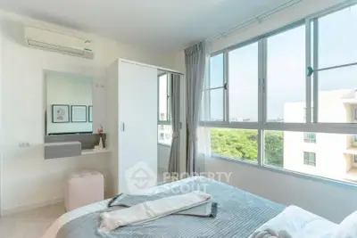 Bright and airy bedroom with large windows and modern decor in a high-rise apartment.