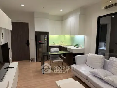 Modern living room with open kitchen, sleek furniture, and ambient lighting in a stylish apartment.