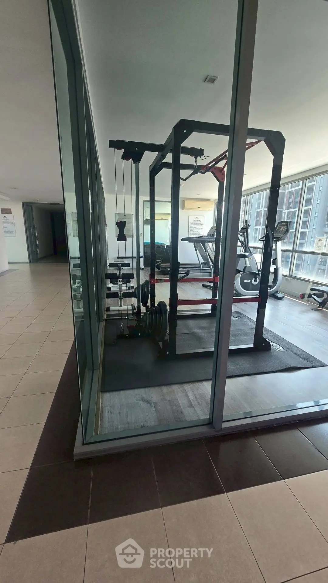 Modern gym with glass walls and fitness equipment in a residential building.