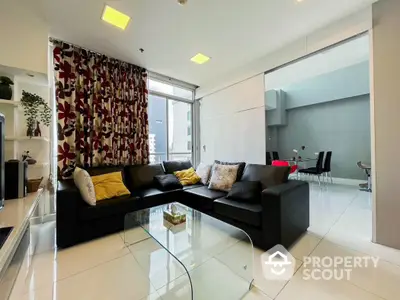 Modern living room with sleek black sofa and glass coffee table in bright apartment