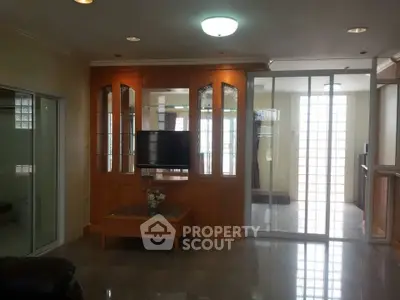 Spacious living room with elegant wooden cabinetry and modern glass doors.