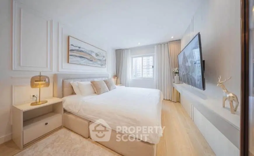 Luxurious bedroom with modern decor, large bed, and wall-mounted TV in a bright, airy space.