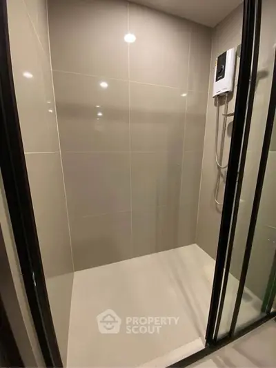 Modern bathroom shower area with sleek glass doors and electric water heater.