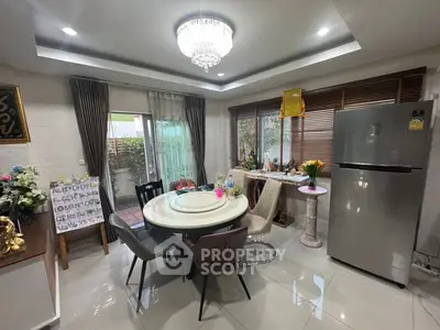 Modern dining area with elegant chandelier and large fridge in stylish home.