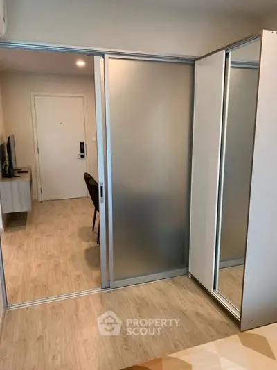 Modern bedroom with sliding frosted glass doors and wooden flooring