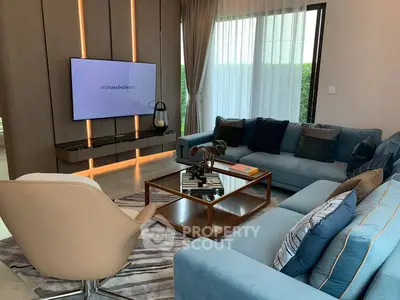 Luxurious modern living room with plush blue sofas and sleek TV setup, perfect for relaxation.