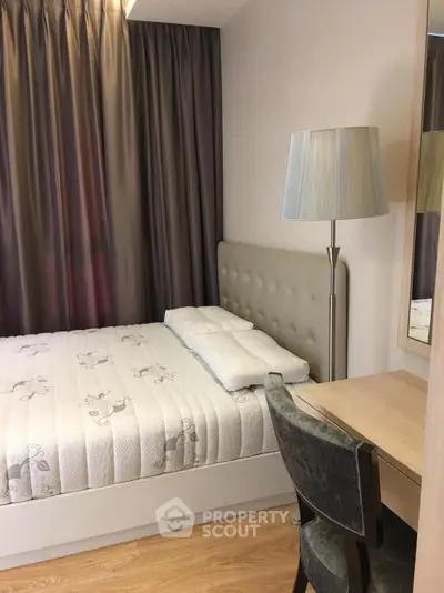 Cozy bedroom with modern decor, featuring a comfortable bed, stylish lamp, and elegant curtains.
