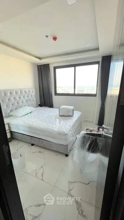 Modern bedroom with elegant decor and large window offering natural light