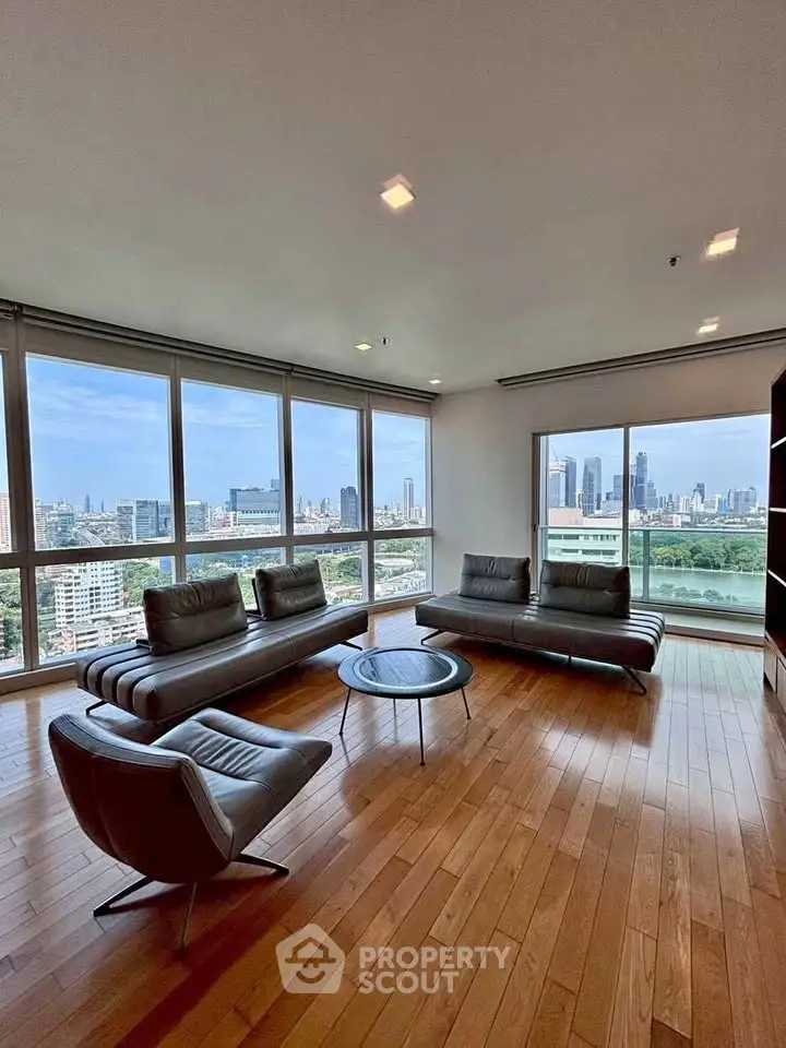 Spacious living room with panoramic city views and modern furniture in high-rise apartment.
