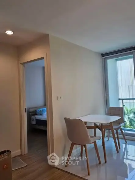 Modern apartment interior with dining area and bedroom view, featuring sleek furniture and natural light.