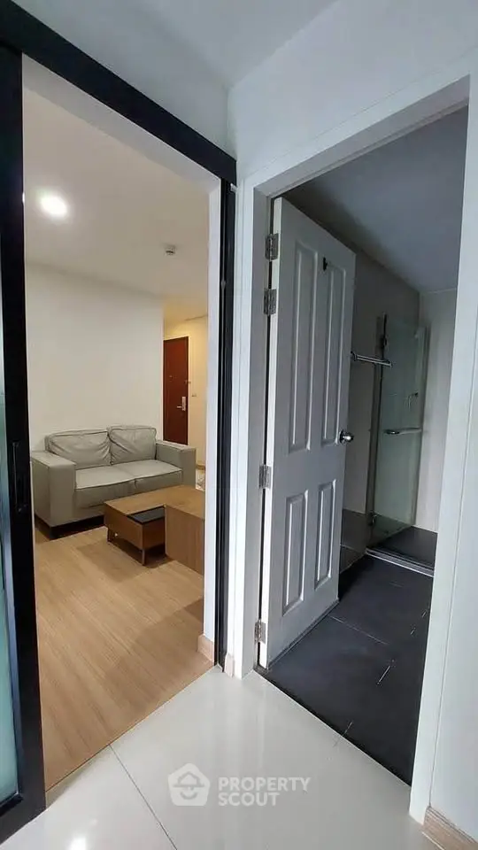 Modern apartment interior with cozy living room and bathroom entrance, featuring sleek design and neutral tones.