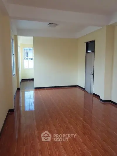 Spacious empty room with wooden flooring and natural light, ideal for customization.