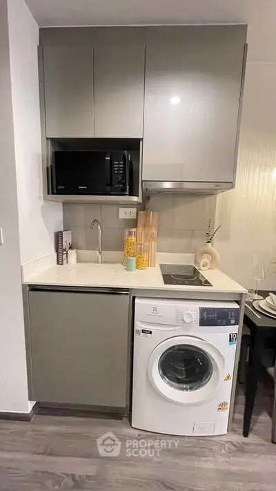 Modern compact kitchen with washing machine and microwave, ideal for urban living.