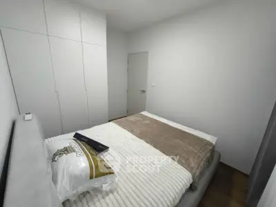 Modern bedroom with sleek white wardrobe and cozy bedding in a minimalist design.