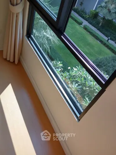 Bright room with large window offering lush garden view, perfect for nature lovers.