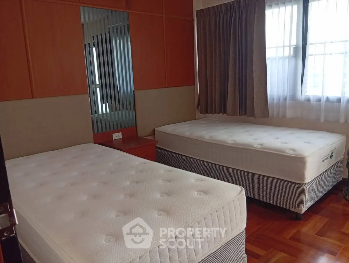 Spacious bedroom with twin beds and natural light, perfect for comfort and relaxation.