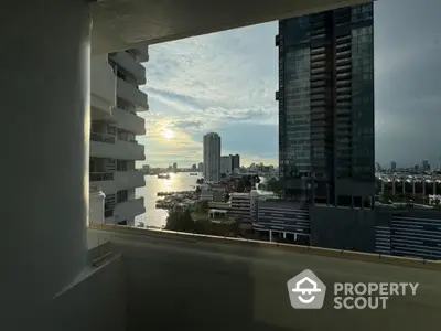 Stunning cityscape view from a high-rise balcony overlooking a river at sunset.