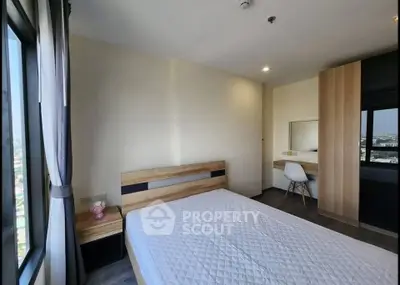 Modern bedroom with city view, featuring a stylish bed and workspace.