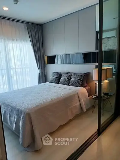 Modern bedroom with stylish decor and large window offering natural light.