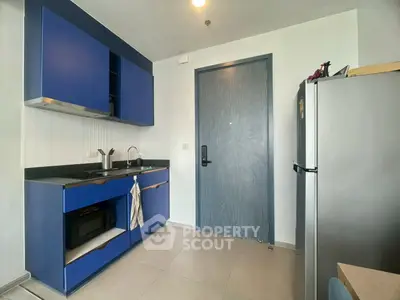 Modern kitchen with blue cabinets and sleek appliances in a stylish apartment.
