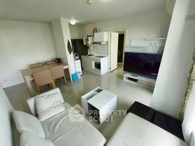 Modern living room with open kitchen, sleek furniture, and large TV, perfect for urban living.