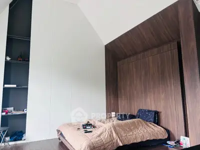 Modern bedroom with sleek wooden paneling and cozy bedding in contemporary home.