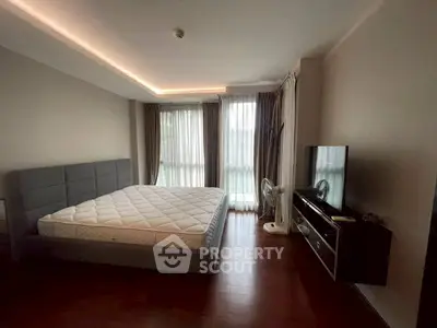 Spacious bedroom with modern decor and large windows for natural light