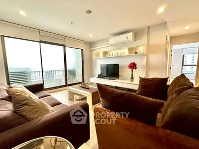 Spacious living room with modern decor and large windows leading to a balcony.
