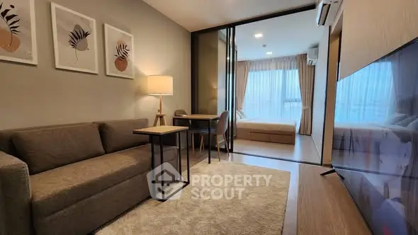 Modern living room with cozy sofa, stylish decor, and view into a bright bedroom.
