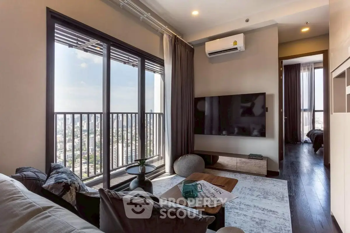 Modern living room with city view, large TV, and stylish decor in high-rise apartment.