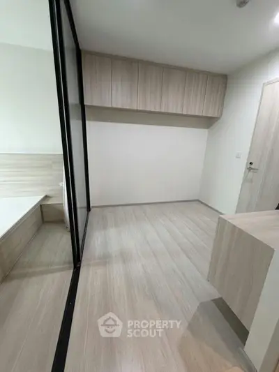 Modern minimalist bedroom with wooden flooring and built-in storage cabinets.