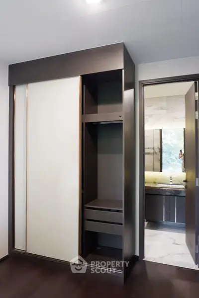 Modern bedroom with sleek wardrobe and view into luxurious bathroom