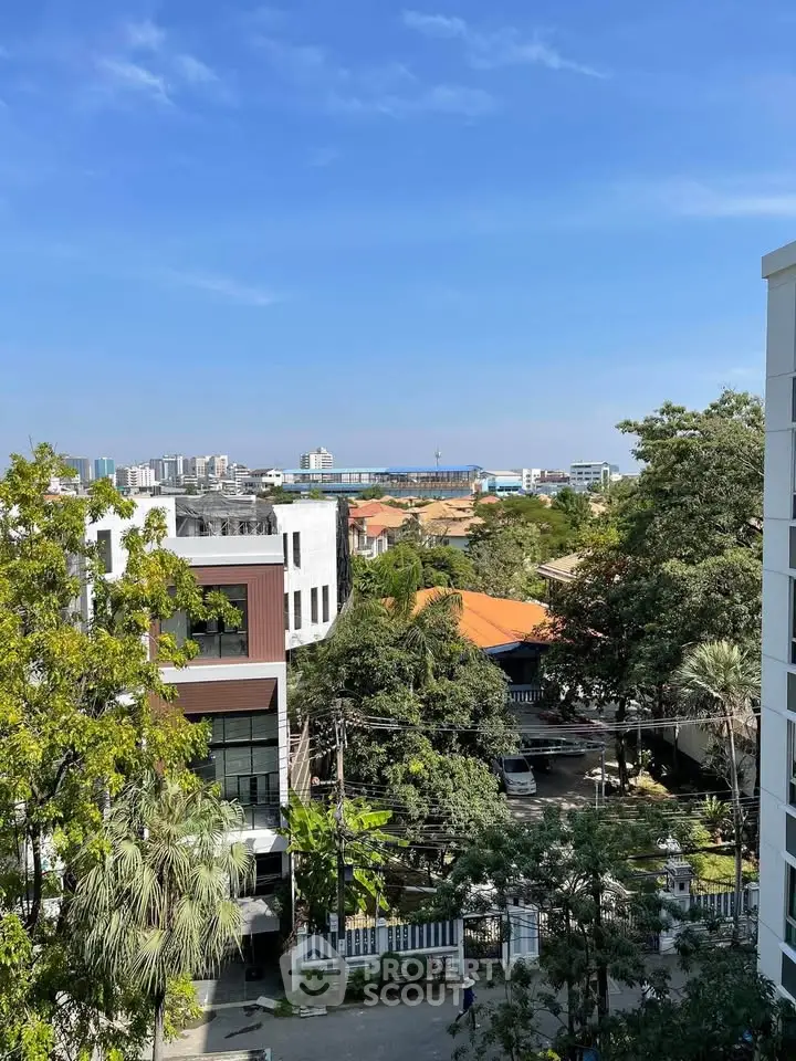 Stunning cityscape view from a high-rise building balcony, showcasing lush greenery and urban skyline.
