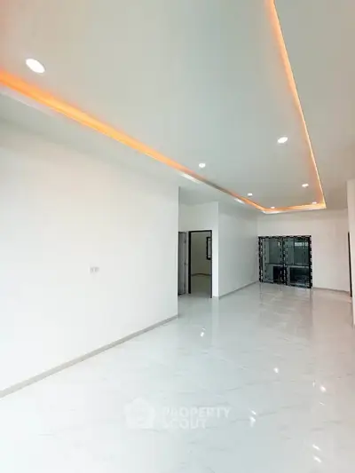 Spacious modern living room with sleek lighting and glossy white flooring