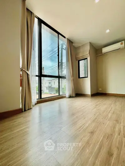 Spacious modern living room with large windows and wooden flooring.