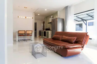 Modern living room with sleek leather sofa and open kitchen layout