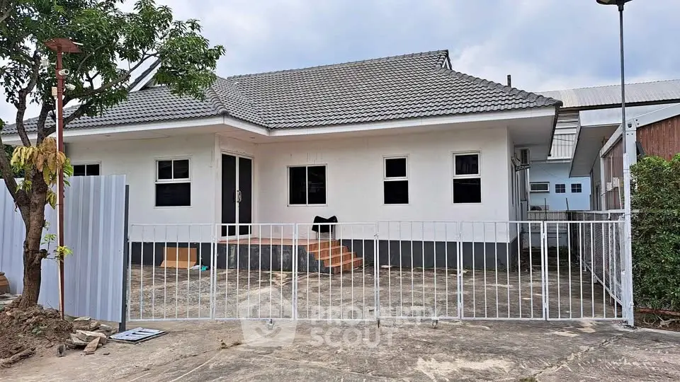 Charming single-story house with a fenced yard and modern roof design.