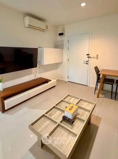 Modern living room with sleek furniture and wall-mounted TV in a cozy apartment.