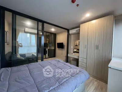 Modern bedroom with glass partition, cozy living area, and stylish decor