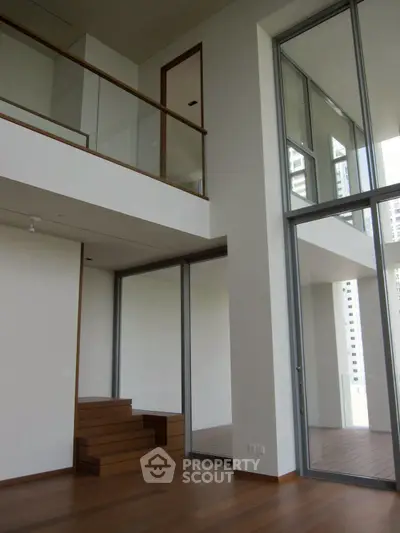 Spacious modern duplex with floor-to-ceiling windows and wooden flooring, offering abundant natural light.