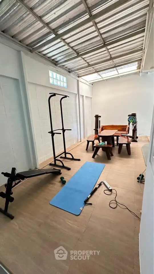 Spacious home gym with exercise equipment and wooden furniture