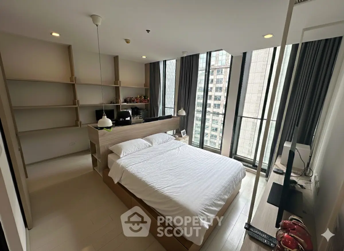 Modern bedroom with large windows and built-in shelves in a high-rise apartment