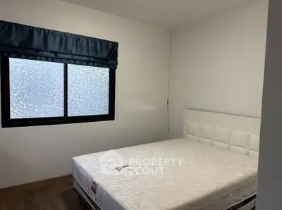 Modern bedroom with minimalist design and large window for natural light.