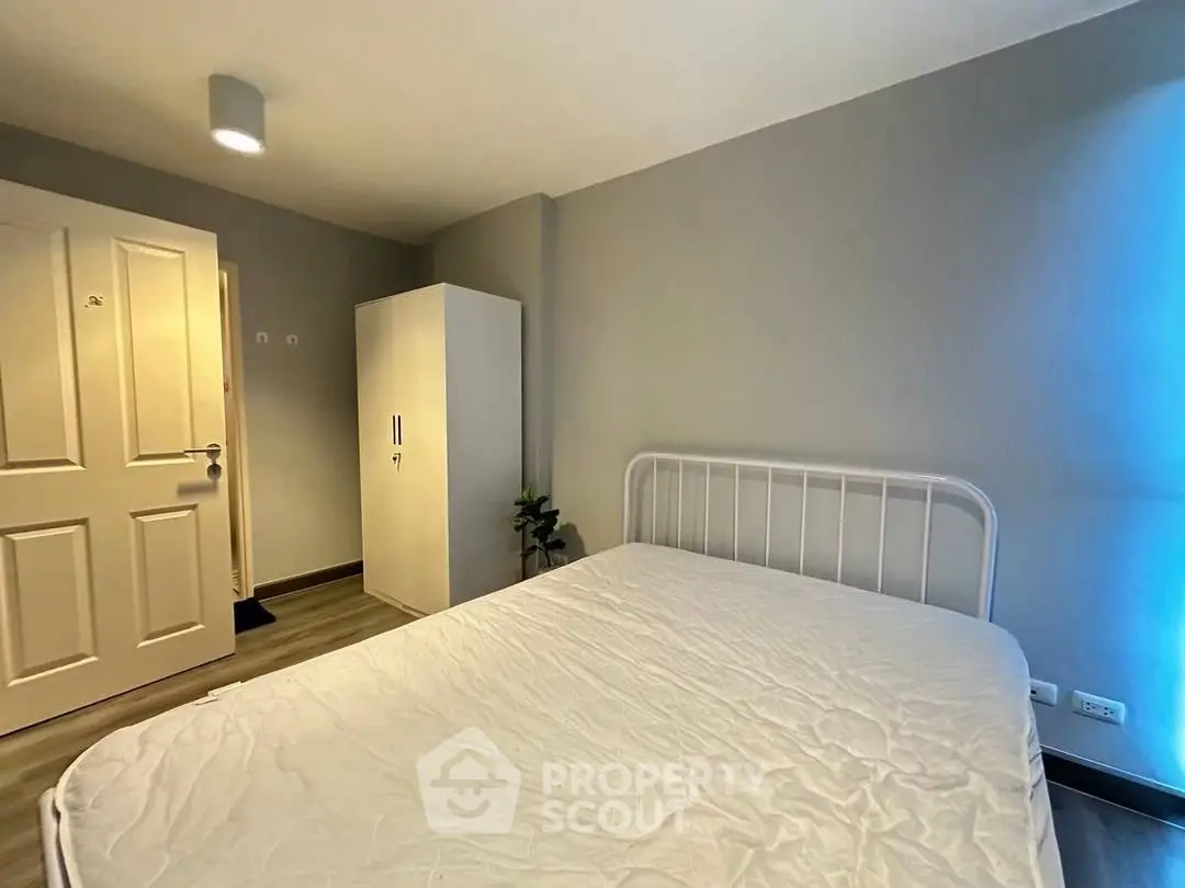 Cozy minimalist bedroom with white bedframe and wardrobe, perfect for modern living.