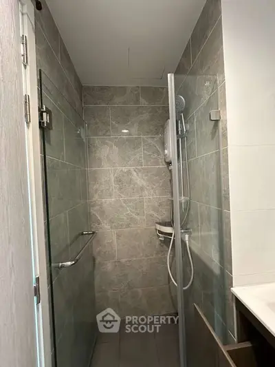 Modern bathroom with sleek glass shower and gray tile walls, perfect for a contemporary home.
