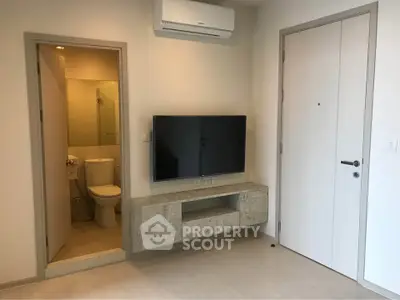 Modern apartment interior with wall-mounted TV and air conditioning, featuring a compact bathroom.