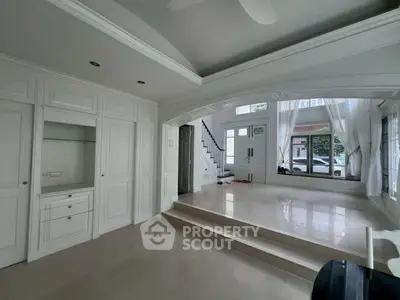 Spacious living room with elegant white interiors and large windows offering natural light.