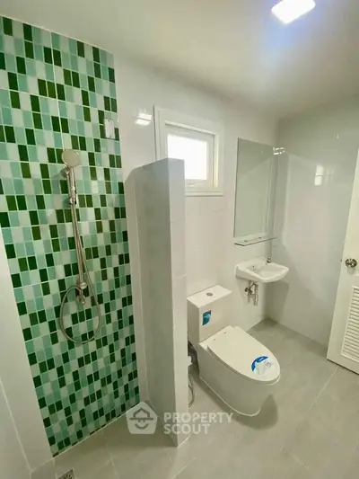 Modern bathroom with green mosaic tiles and sleek fixtures