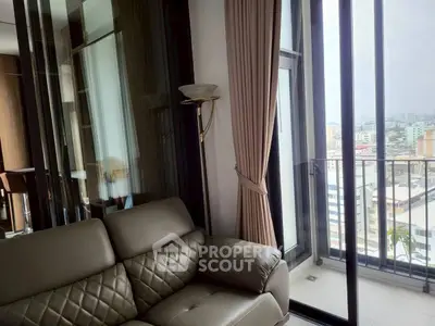Modern living room with balcony and city view, featuring elegant leather sofa and floor-to-ceiling windows.
