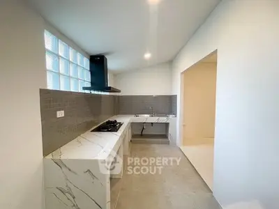 Modern kitchen with sleek marble countertops and gas stove in a bright, minimalist design.
